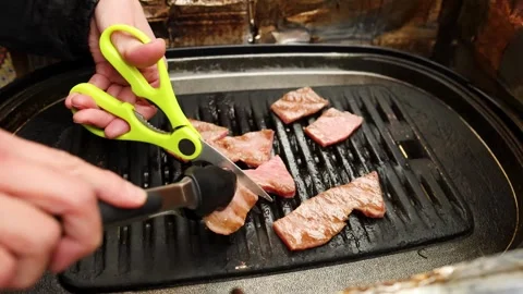 Chef using lime green kitchen scissors and tongs to cut premium wagyu beef .. Stock Footage 333320413