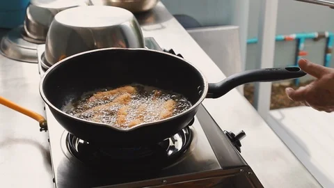 Chef using metal tong to flip deep fried shrimp before taking it out of oil Stock-Footage 113383362
