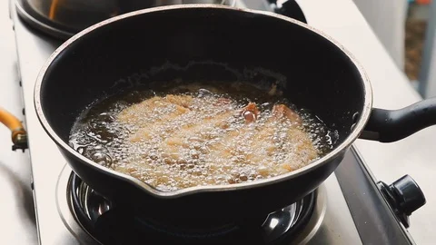 Chef using metal tongs to flip deep fried shrimp in pan with boiling oil Video stock 113383408