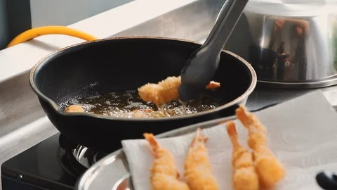 Chef using metal tongs to take deep fried shrimp out of oil in pan Stock-Footage 113383314