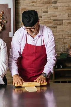 Chef using rolling pin preparing dough in restaurant kitchen Stock Photos
