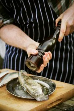 Chef using a salt mill, grinding salt onto a fresh fish. 写真素材