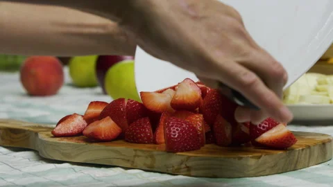 Chef using sharp knife to push diced strawberries onto chopping board - closeup Stock Footage 341229720