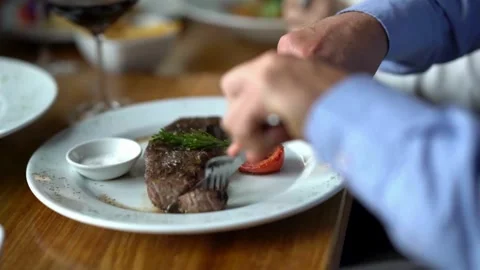 Chef using a sharp knife to slice a steak, ensuring each piece is tender 库存影片 336581511