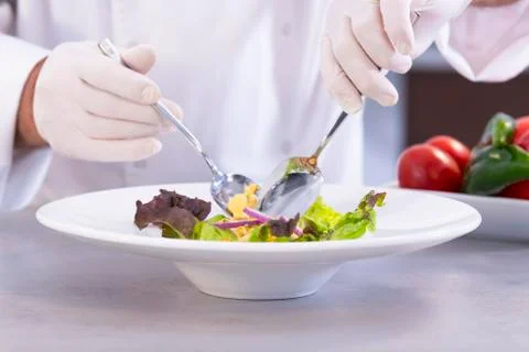 Chef using spoons to prepare a delicious salad Stock Photos