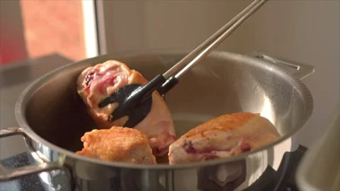 A Chef using a tong  to remove browned chicken from a hot pot Stock Footage 318850645