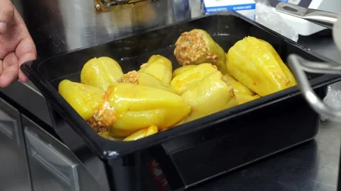 A chef using tongs putting stuffed peppers into a metal container in the kitchen Stock Footage 341550247