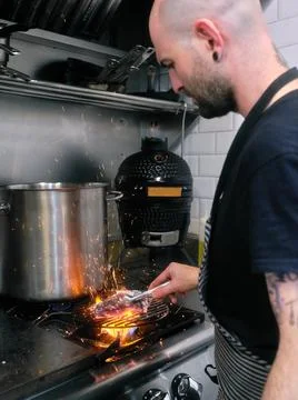 Chef using tongs to remove charcoal from the fire in a restaurant Stock Photos