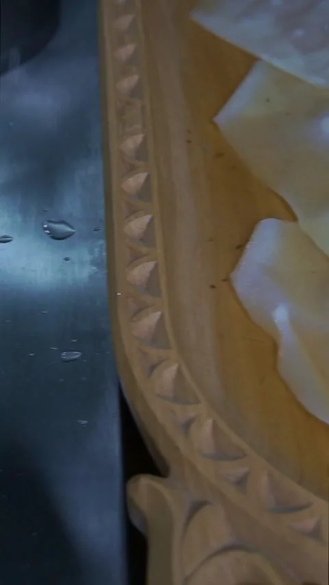 Chef using a wire skimmer to place the first boiled dough sheet into a carved wo Stock Footage 342627856