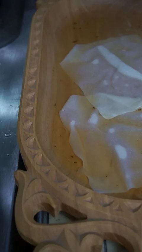 Chef using a wire skimmer to place the first boiled dough sheet into a carved wo Stock Footage 342627857
