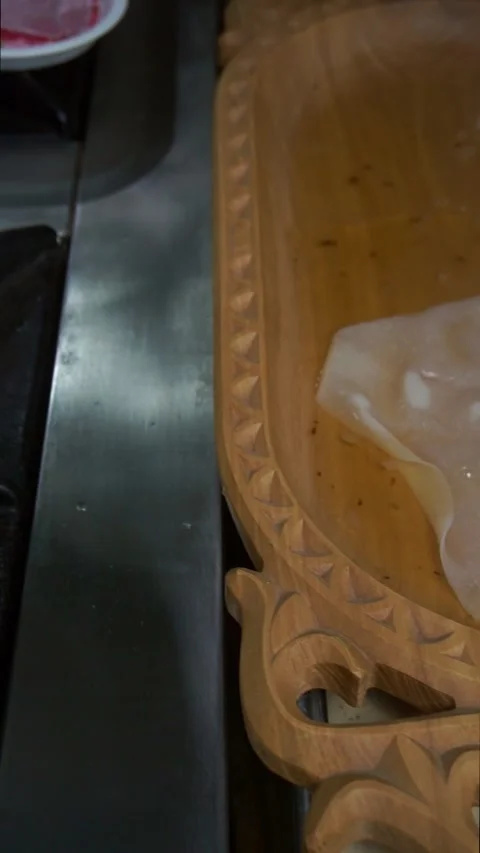 Chef using a wire skimmer to place the first boiled dough sheet into a carved wo Stock Footage 342627882