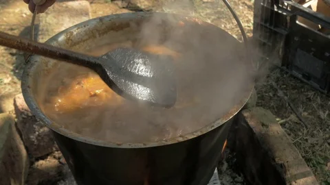 Chef using wooden spoon to mixing meat and vegetables, preparing beef stew. Stock Footage 81556669