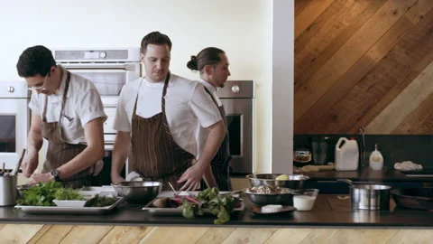 Chef walking past other chefs to his station to peel potatoes in interior kitche Stock Footage 199455887