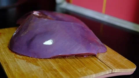 Chef washing fresh raw beef liver and placing it on wooden cutting board for Stock Footage 346262493