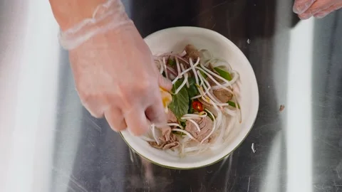 A chef wearing disposable gloves squeezes a fresh lemon into a dish. Video stock 152256866