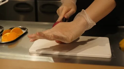 Chef Wearing Gloves Slicing Fresh Red Apple on White Cutting Board Stock Footage 345292940
