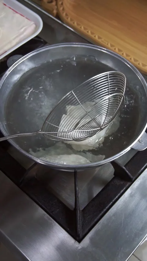 Chef wearing white gloves boiling fresh dough sheets for beshbarmak in a metal p Stock Footage 342627822