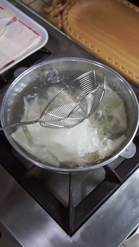 Chef wearing white gloves boiling fresh dough sheets for beshbarmak in a metal p Stock Footage 342627824