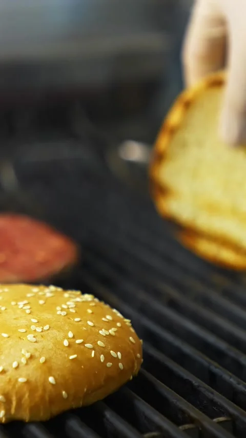 Chef wearing white gloves flips toasted sesame seed burger buns on hot comm.. Stock Footage 337469512