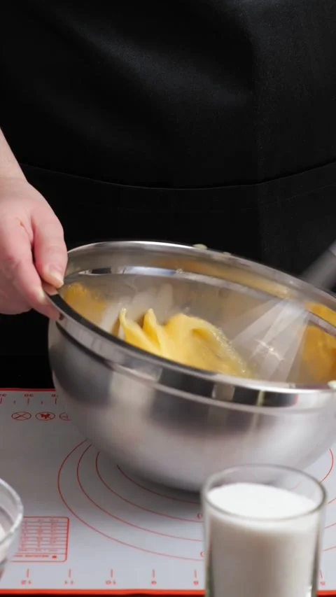 Chef whisking eggs and milk in a stainless steel bowl for a homemade recipe Stockbeeldmateriaal 342907170