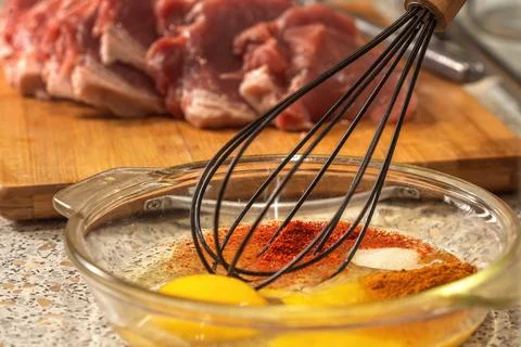 Chef whisks raw eggs, salt, red pepper and paprika for a liaison before sau.. Foto stock