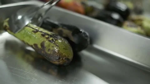 The chef with white-gloved hands shifts fried vegetables from the grill into a Stock Footage 250149612