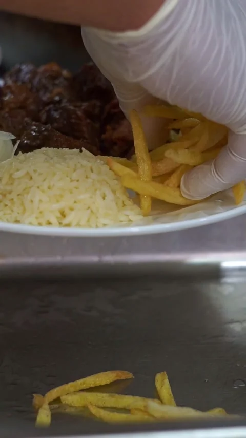 Chef in white gloves adding crispy french fries to a traditional meat and rice p Stock Footage 342345282