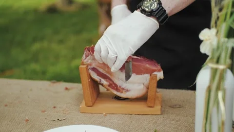 Chef in white gloves cuts dried meat with a knife and places it on a plate Stock-Footage 310249060