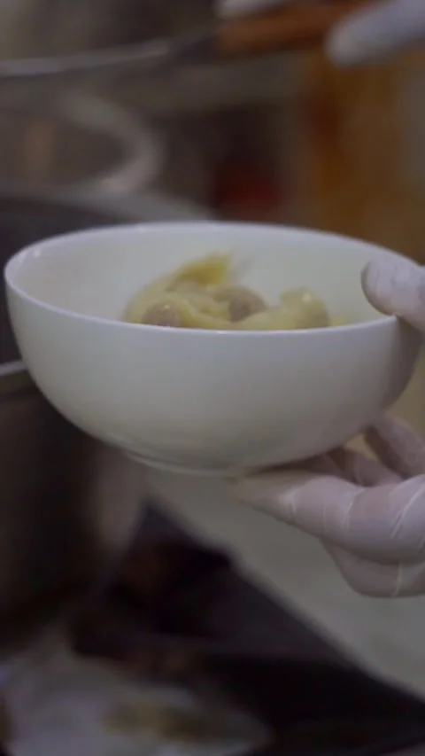 Chef in white gloves serving freshly boiled traditional dumplings from a wire sk Stock Footage 342345264