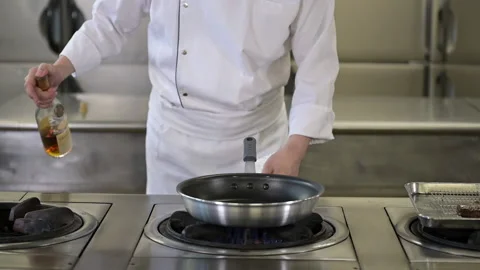 A chef in a white uniform creating a flambe flames with alcohol. Stock Footage 187578810