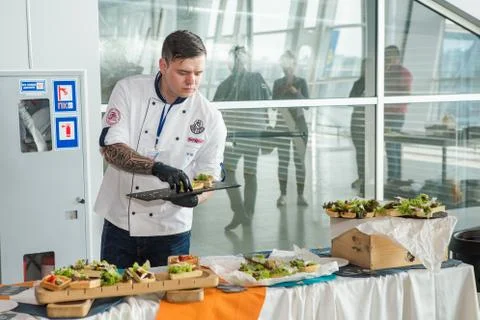 Chef in white uniform serving snacks on table for degustation in Lviv airport Stock Photos