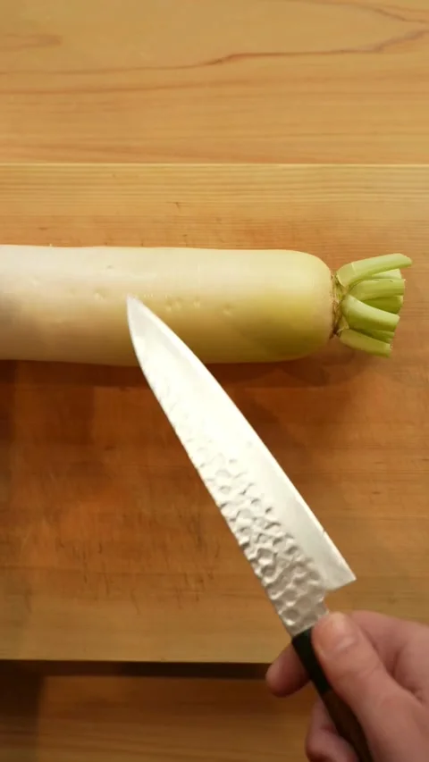 Chef wipes a knife next to a white radish Video stock 331770276