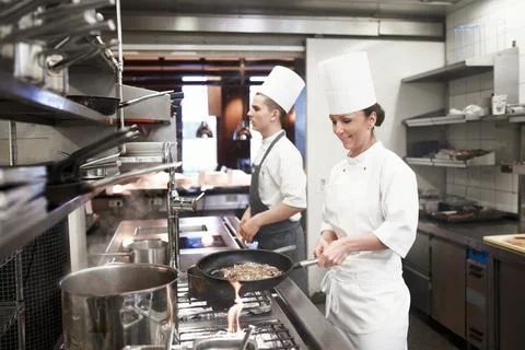 Chef, woman and frying in restaurant kitchen, catering service and prepare food Stock Photos