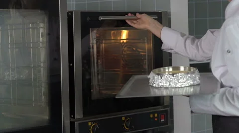 Chef woman doing baking and placing a cake in the oven Stock Footage 66985063