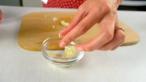 Chef woman hands adding chopped garlic to glass bowl cooking on kitchen. Stock Footage 312398390