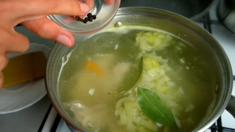 Chef woman hands adding spices into chicken broth with bay leaf, peppercorns. Stock Footage 312451641