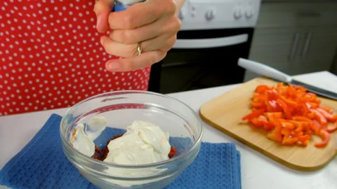 Chef woman hands cooking adding salt to sour cream in bowl with tomato sauce. Stock Footage 312400033