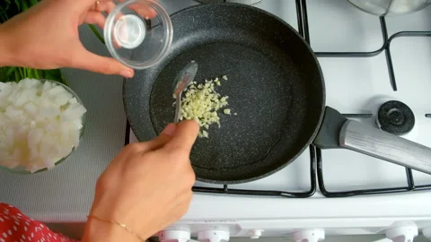 Chef woman hands cooking adding chopped onions garlic to frying pan on kitchen. Stock Footage 312400768