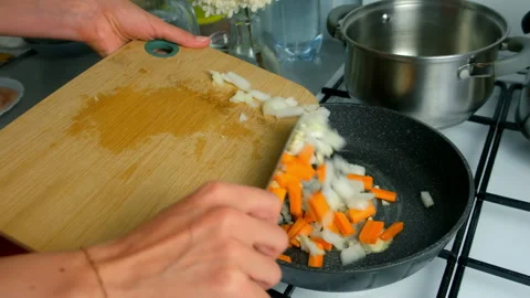 Chef woman hands cooking adding chopped onions garlic carrots to frying pan. Stock Footage 312449090