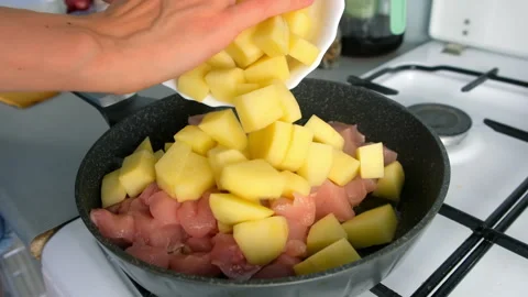 Chef woman hands cooking adding potatoes to chicken meat into frying pan. Stock Footage 312469013