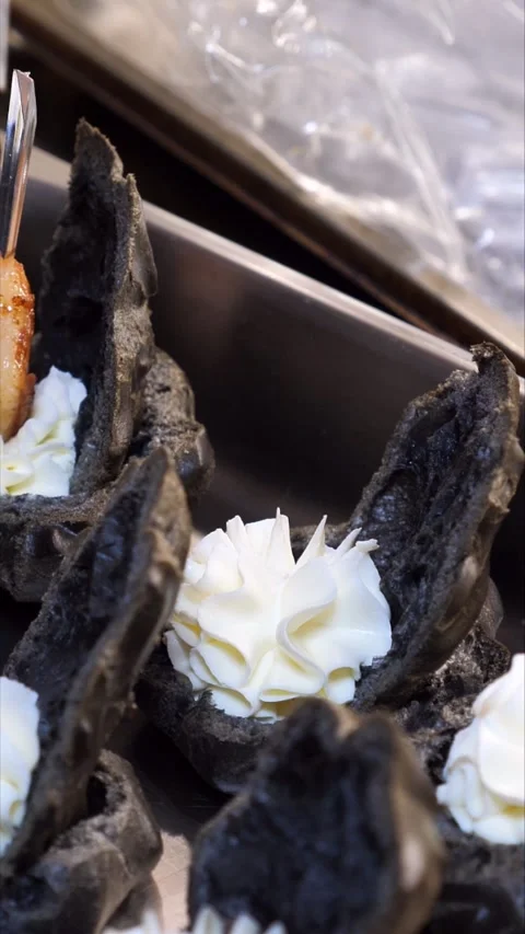 Chef&amp;#039;s hand placing a grilled shrimp on a gourmet black profiterole. Stock-Footage 342149783