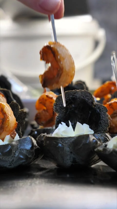 Chef&amp;#039;s hand placing a grilled shrimp on a gourmet black profiterole. Stock-Footage 342149802