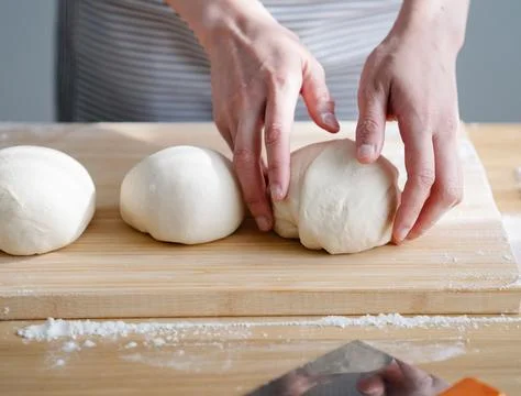 Chef&amp;#039;s Hands Kneading Bread Dough on a Floured Worktop Stock Photos