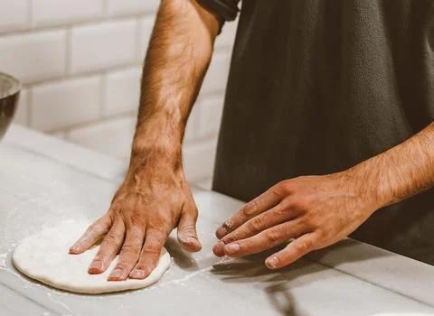Chef&amp;#039;s Hands Kneading Bread Dough on a Floured Worktop Stock Photos