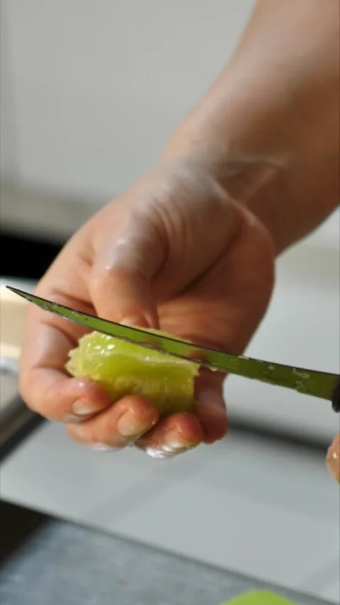 A chef&amp;#039;s hands use a knife to cut fresh green lime in the kitchen. Stock Footage 342150477