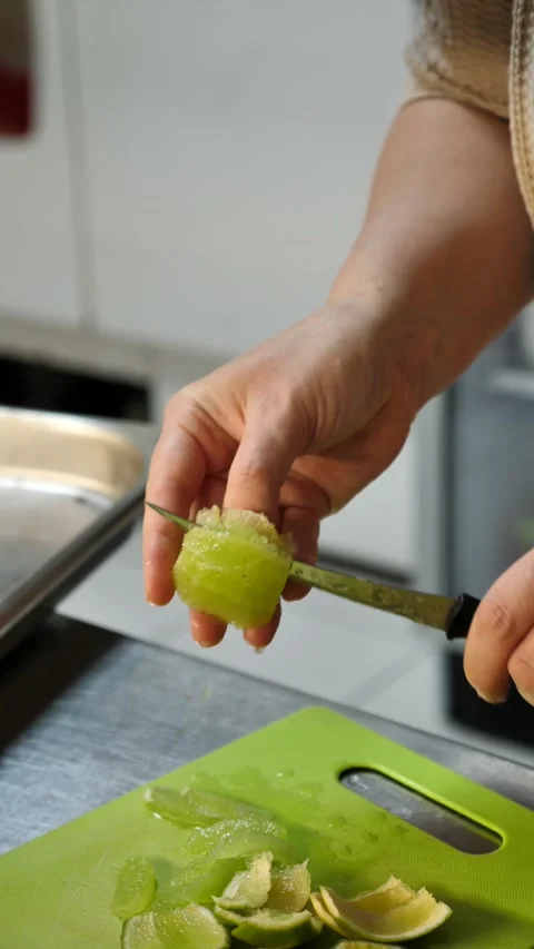 A chef&amp;#039;s hands use a knife to cut fresh green lime in the kitchen. Stock Footage 342150827