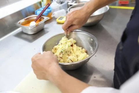 The chef's blurred background is grinding the potatoes before cooking in the  Stock Photos