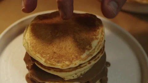 Chef's hand adding fourth pancake uphill with chocolate cream in slow motion Stock-Footage 151361900
