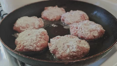 Chef's hand carefully placing several raw minced meat cutlets, breaded Stock Footage 345601581