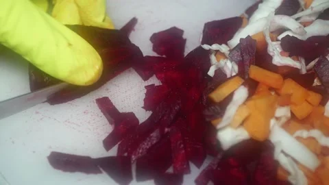 The chef's hand cuts red beets with a knife on a cutting board for cooking r 库存影片 231326412